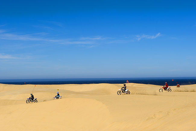 Four dirt bikes riding on the dunes